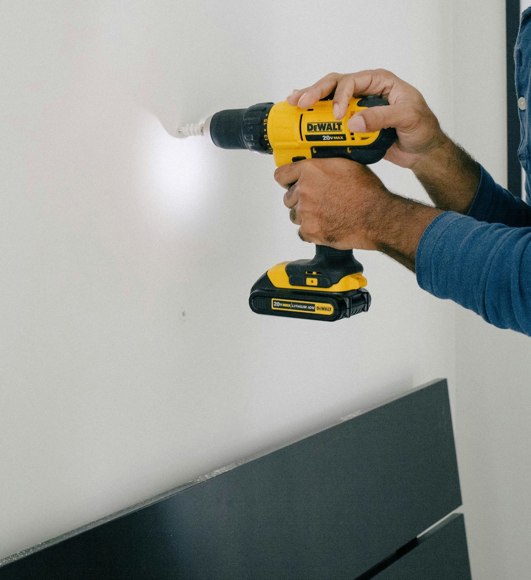 person holding yellow and black cordless hand drill