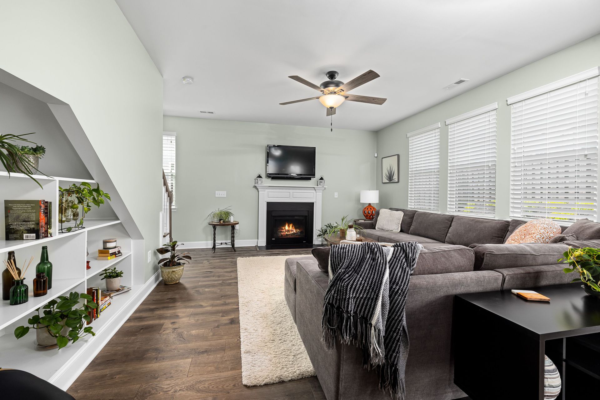 Stylish living room featuring a large sectional sofa, fireplace, and indoor plants for a cozy ambiance.